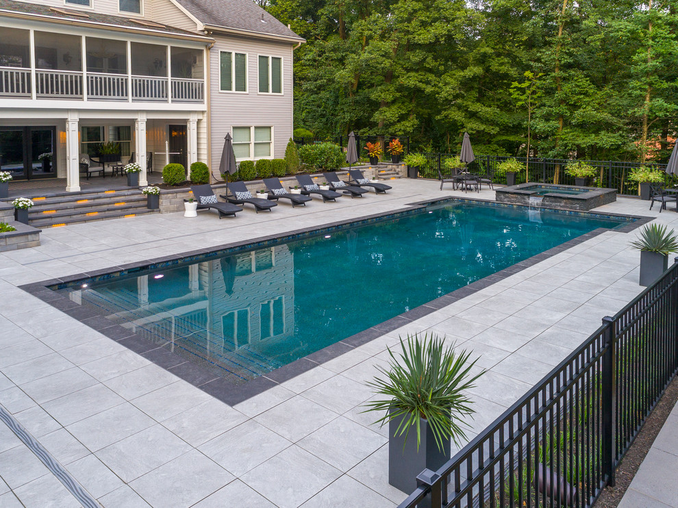 Diseño de casa de la piscina y piscina alargada clásica renovada grande rectangular en patio trasero con adoquines de hormigón
