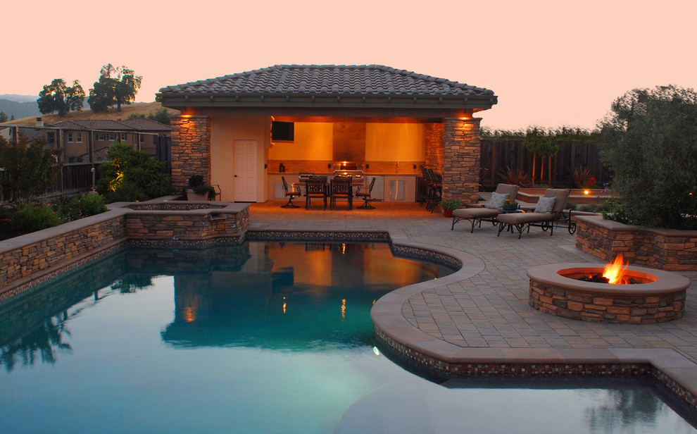 Foto di una grande piscina naturale tradizionale personalizzata dietro casa con una vasca idromassaggio e pavimentazioni in cemento
