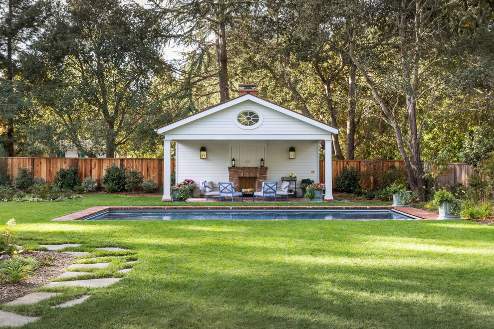 Imagen de casa de la piscina y piscina alargada clásica grande rectangular en patio trasero con adoquines de ladrillo