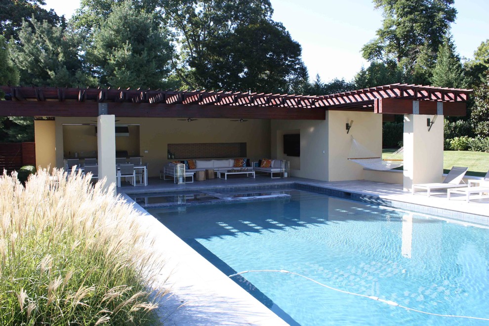 Пример оригинального дизайна: большой естественный, прямоугольный бассейн на заднем дворе в стиле модернизм с домиком у бассейна и покрытием из каменной брусчатки