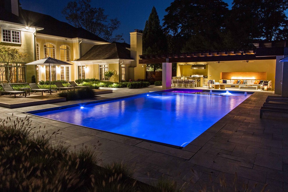 Esempio di una grande piscina naturale minimalista rettangolare dietro casa con una dépendance a bordo piscina e pavimentazioni in pietra naturale