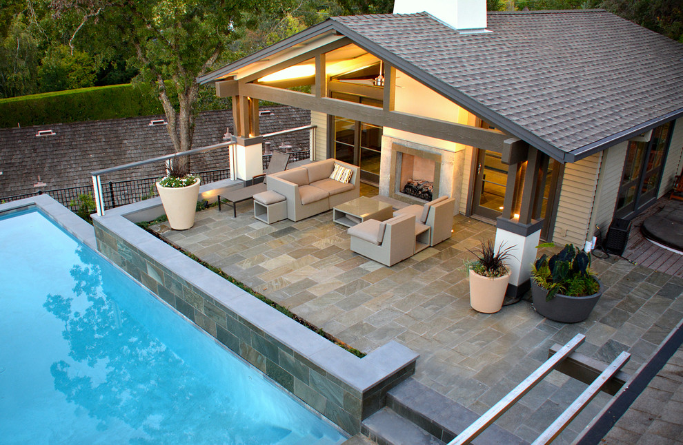Cette image montre une grande piscine arrière design rectangle avec des pavés en pierre naturelle.