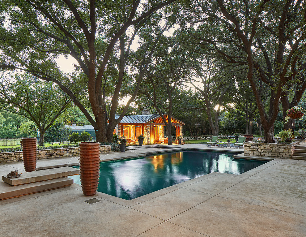 Klassisches Sportbecken hinter dem Haus in rechteckiger Form mit Wasserspiel und Betonplatten in Dallas