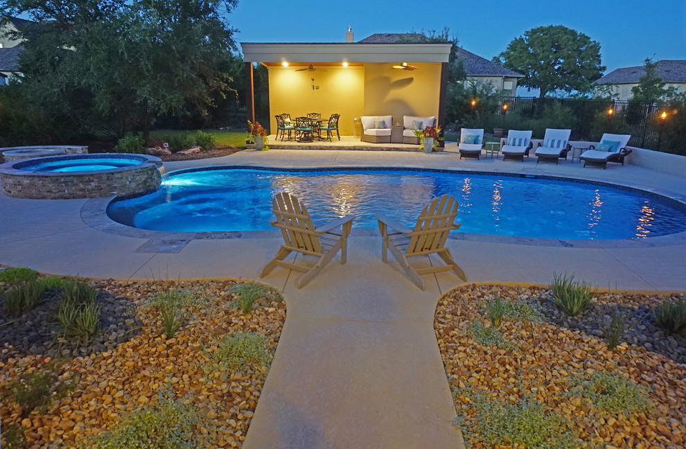 На фото: большой бассейн произвольной формы на заднем дворе в классическом стиле с домиком у бассейна и покрытием из бетонных плит с