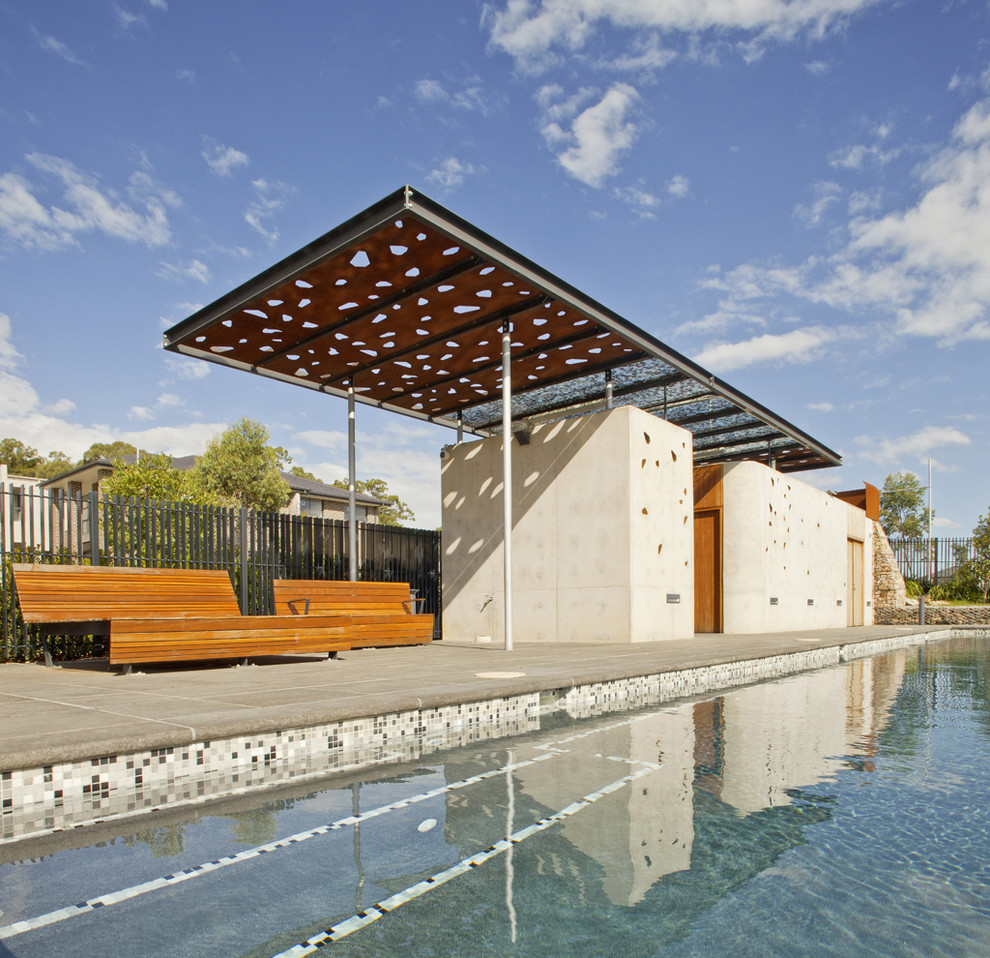 Foto på en stor funkis träningspool, med poolhus och naturstensplattor