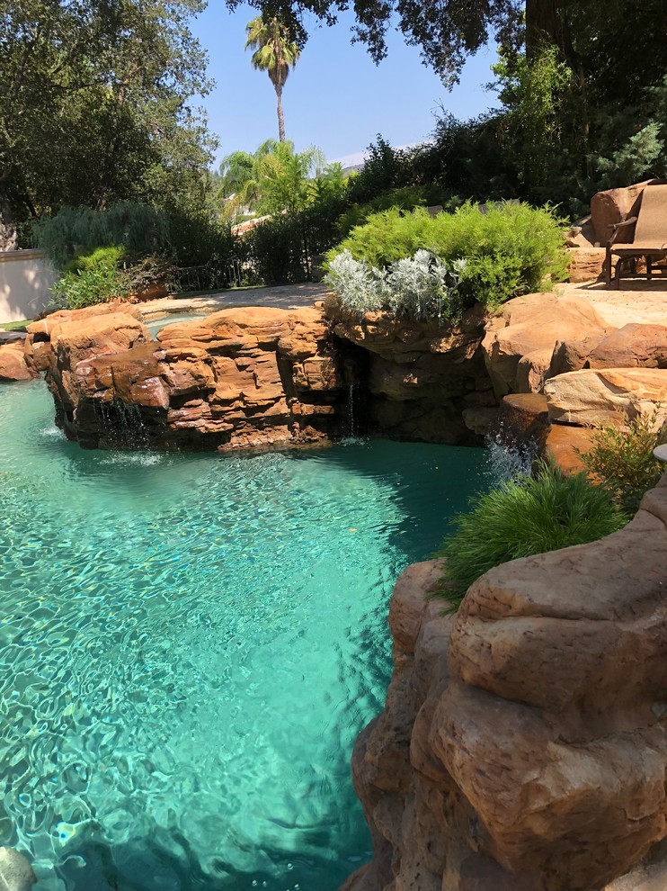 Modelo de piscina exótica grande tipo riñón en patio trasero con adoquines de piedra natural