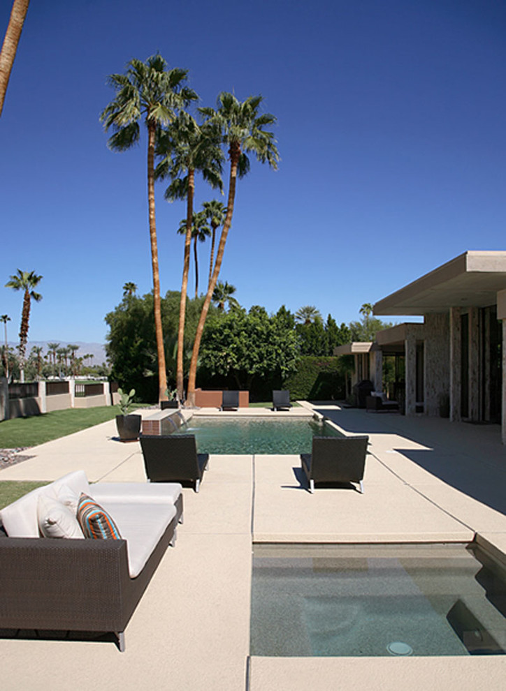 Modelo de piscinas y jacuzzis alargados contemporáneos grandes rectangulares en patio trasero con losas de hormigón
