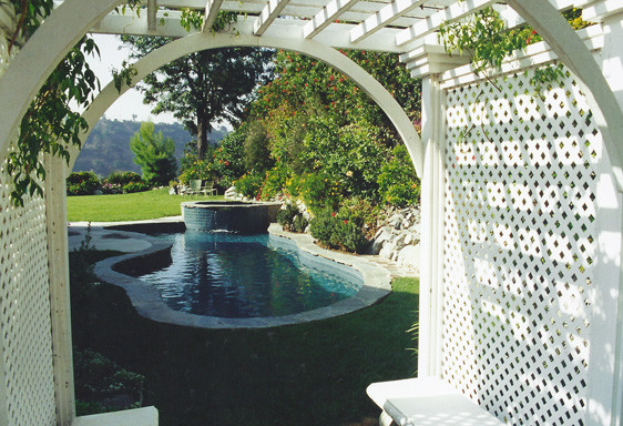 Ispirazione per una piscina tradizionale personalizzata di medie dimensioni e dietro casa con una vasca idromassaggio e pavimentazioni in pietra naturale