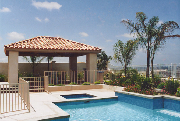 Foto de piscinas y jacuzzis alargados clásicos de tamaño medio rectangulares en patio trasero con losas de hormigón