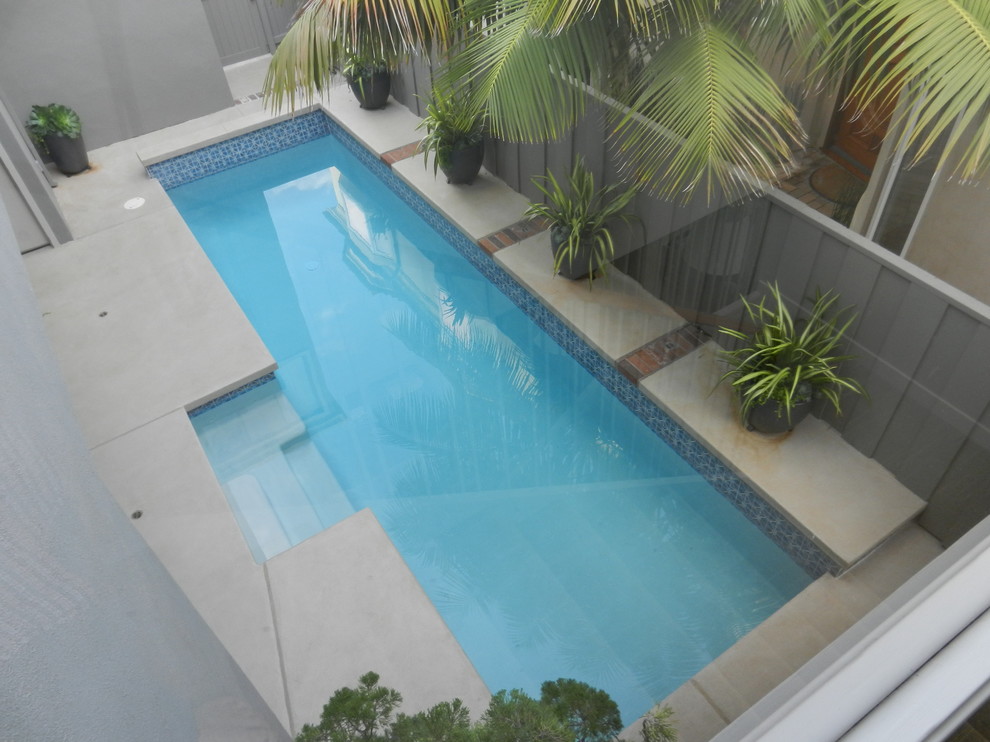 Foto de piscina alargada actual de tamaño medio rectangular en patio con losas de hormigón