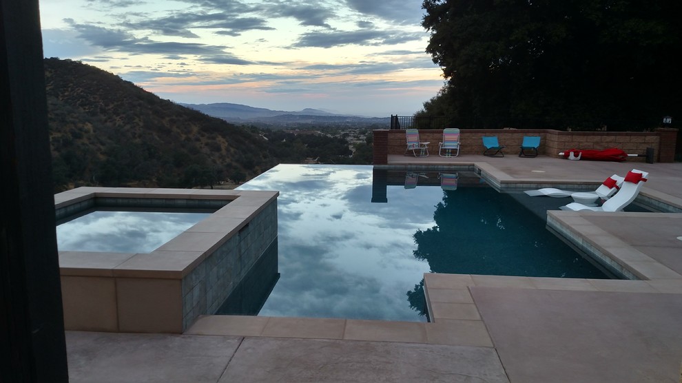 Inspiration for a large contemporary backyard concrete paver and rectangular infinity hot tub remodel in Los Angeles