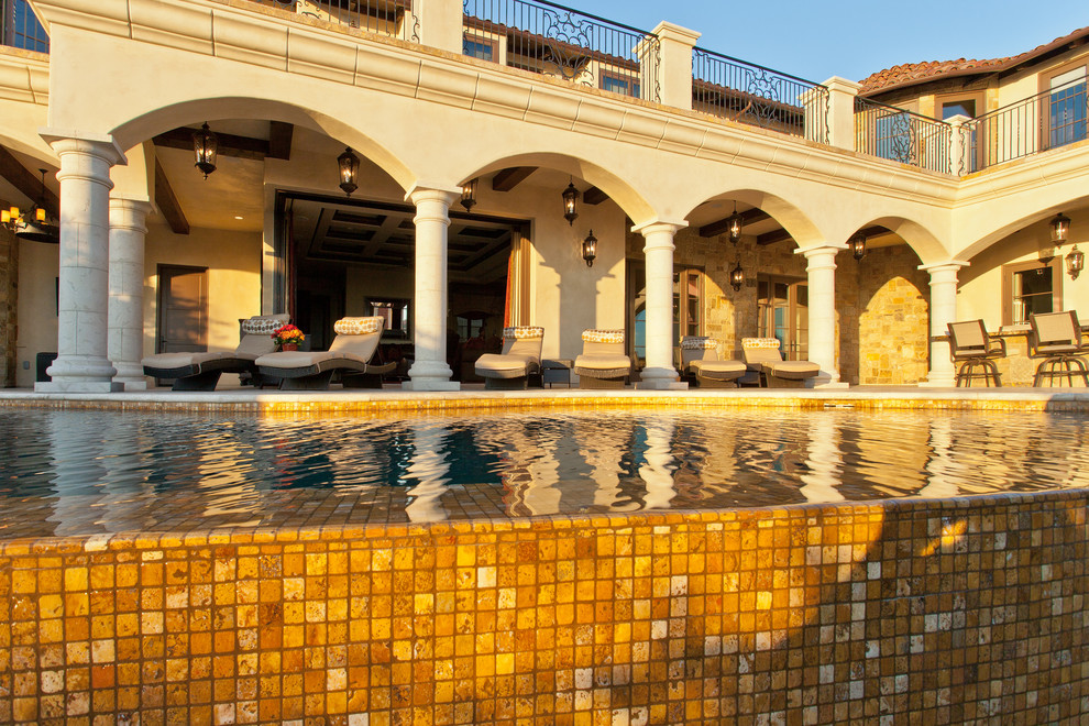 Idée de décoration pour une très grande piscine à débordement méditerranéenne sur mesure avec un point d'eau, une cour et des pavés en pierre naturelle.