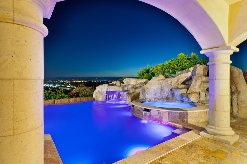 Пример оригинального дизайна: огромный бассейн-инфинити произвольной формы в средиземноморском стиле с фонтаном и покрытием из каменной брусчатки