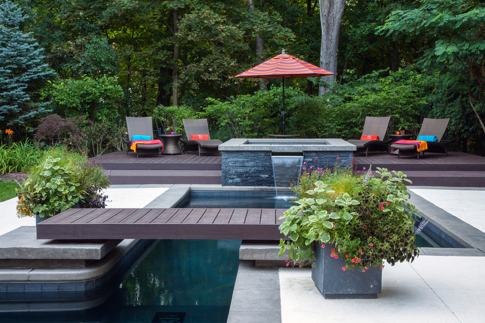 Example of a large trendy backyard pool fountain design in Other with decking