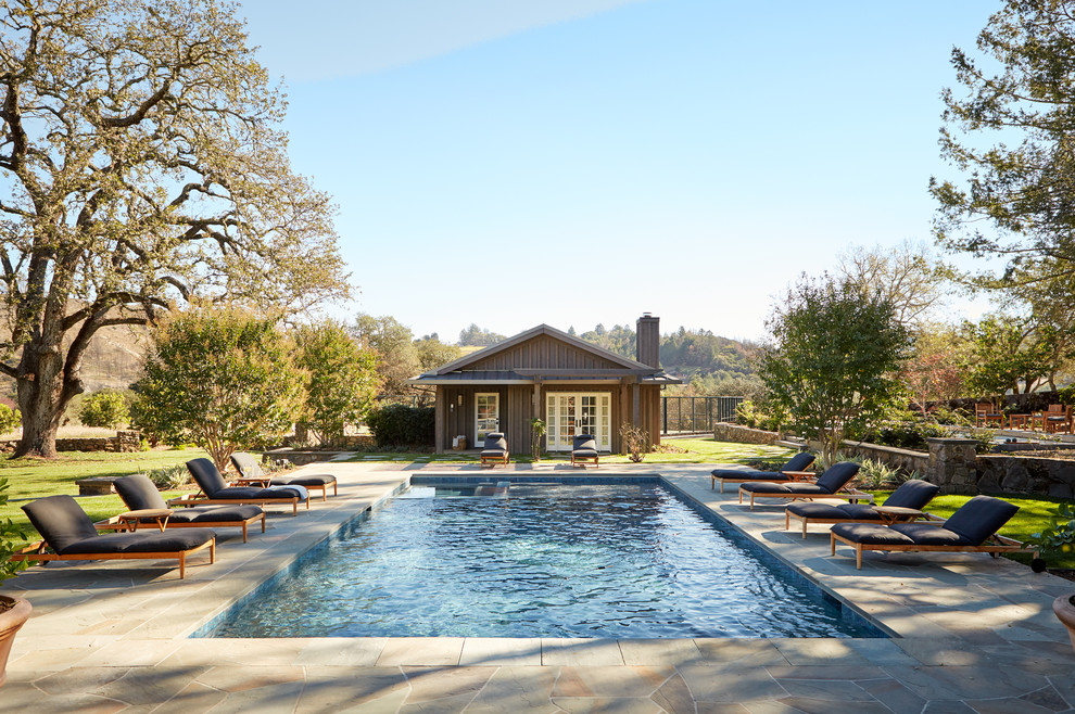 Immagine di una piscina monocorsia country rettangolare dietro casa con una dépendance a bordo piscina e piastrelle