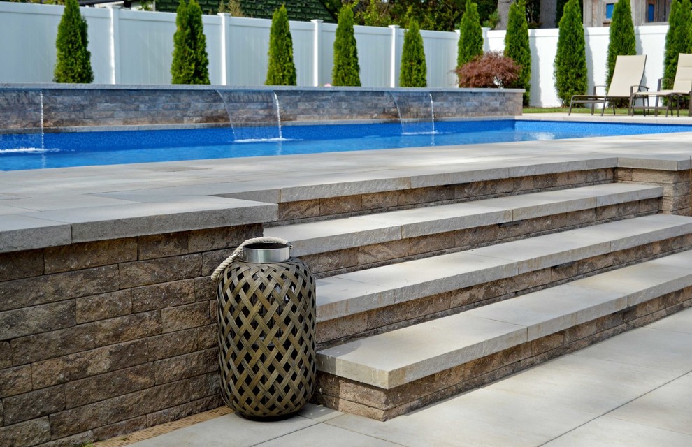 Ejemplo de piscina elevada clásica a medida en patio trasero con adoquines de ladrillo