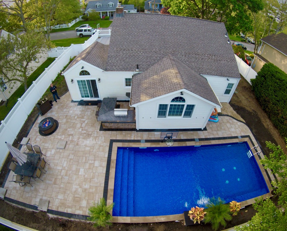 Ejemplo de piscina alargada actual grande rectangular en patio trasero con paisajismo de piscina y adoquines de hormigón