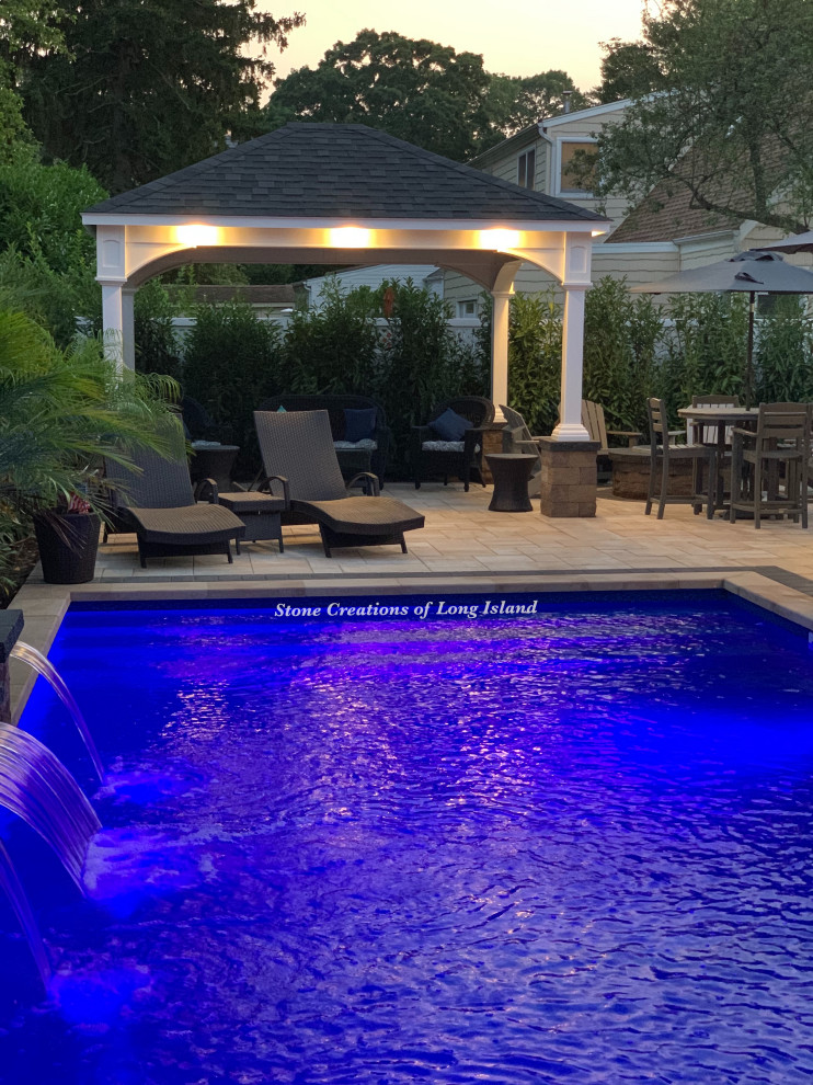 Ejemplo de piscina alargada tradicional grande rectangular en patio trasero con paisajismo de piscina y adoquines de hormigón