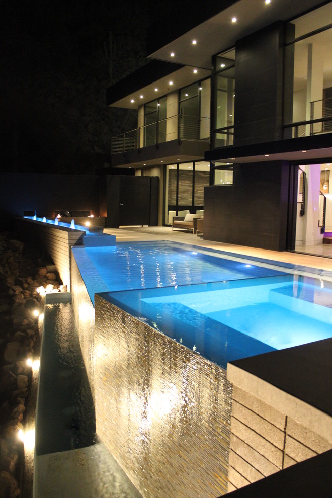На фото: бассейн-инфинити произвольной формы в стиле модернизм с покрытием из плитки и фонтаном с