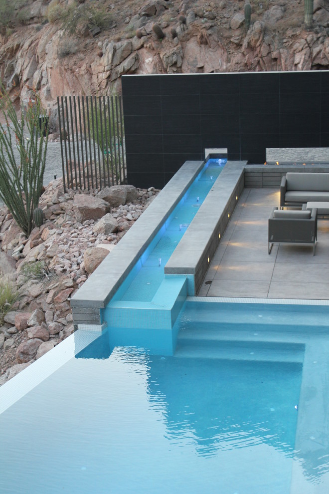 Immagine di una piscina a sfioro infinito minimalista personalizzata con piastrelle