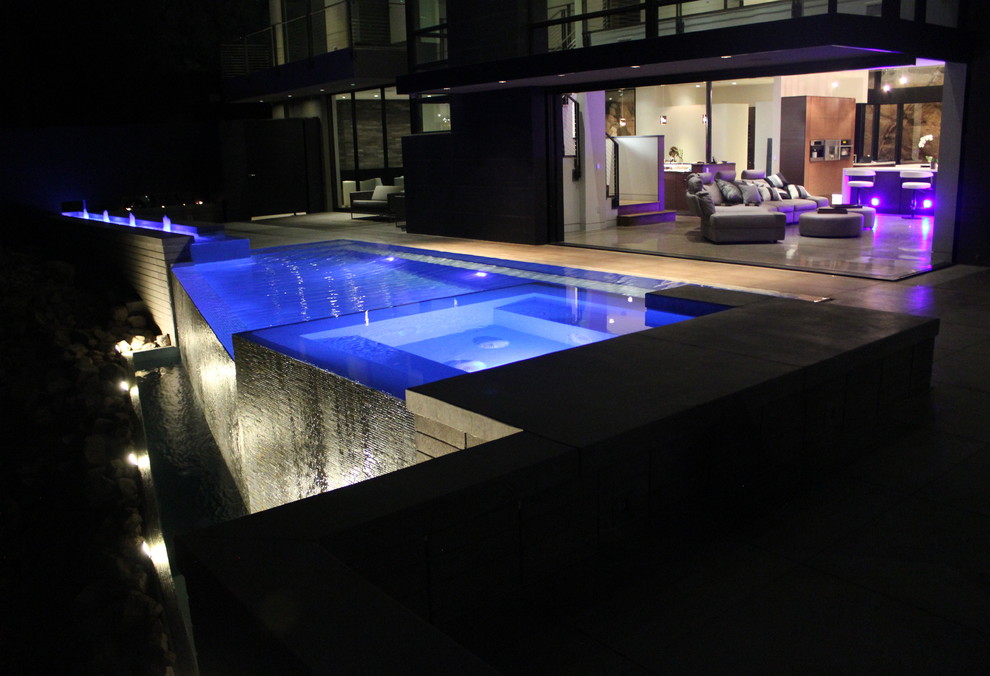 На фото: бассейн-инфинити произвольной формы в стиле модернизм с покрытием из плитки с