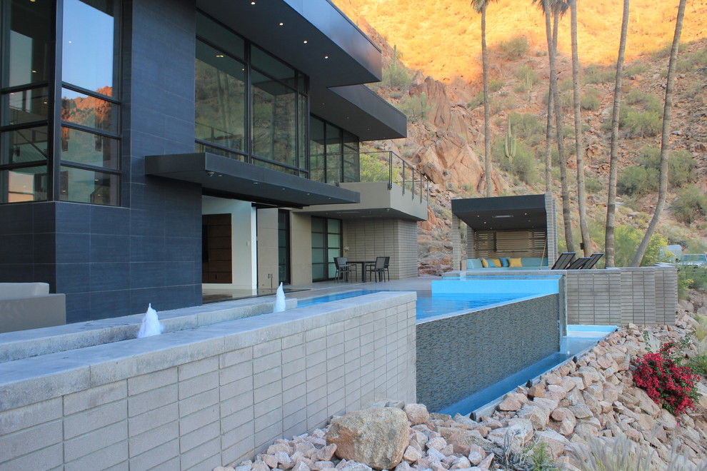 На фото: бассейн-инфинити произвольной формы в стиле модернизм с фонтаном и покрытием из плитки