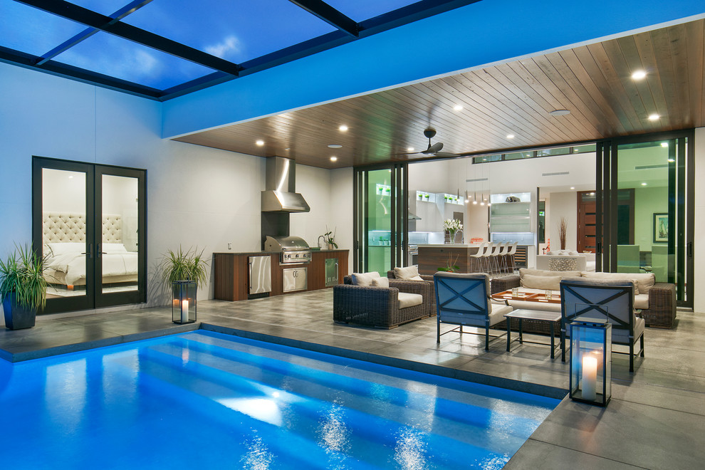Immagine di una piccola piscina monocorsia minimalista personalizzata dietro casa con fontane e lastre di cemento