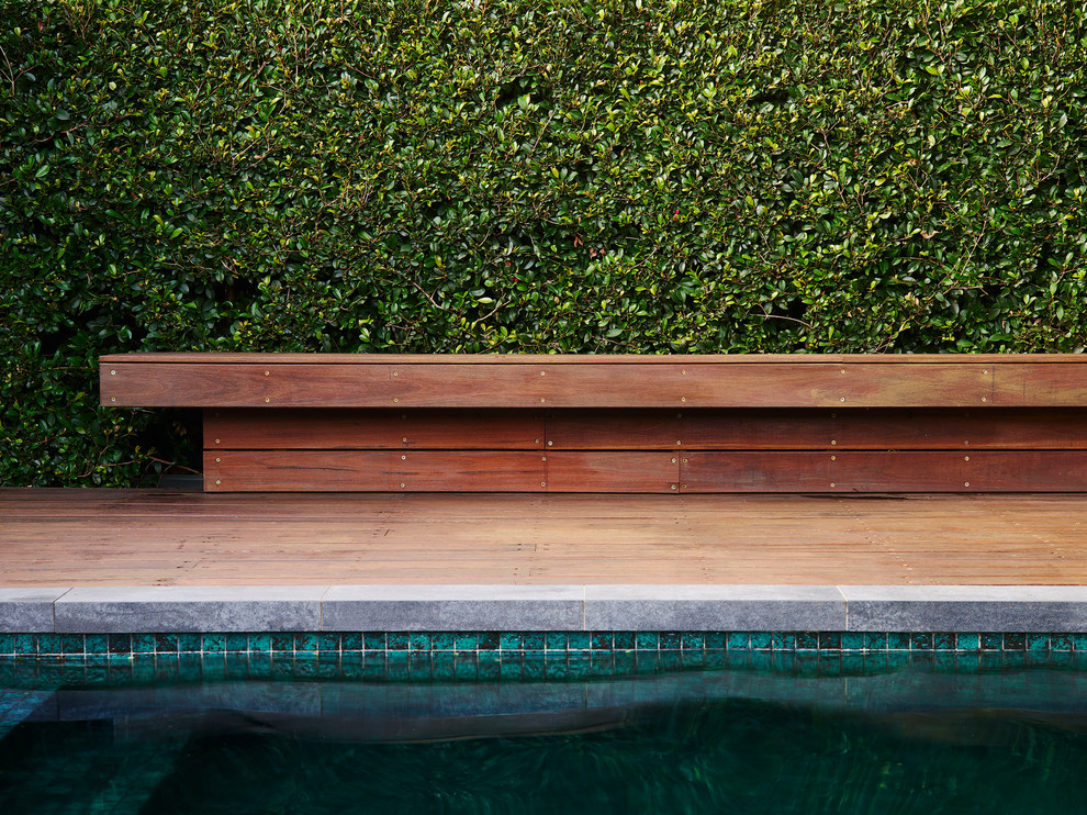Réalisation d'un grand couloir de nage arrière design rectangle avec une terrasse en bois.