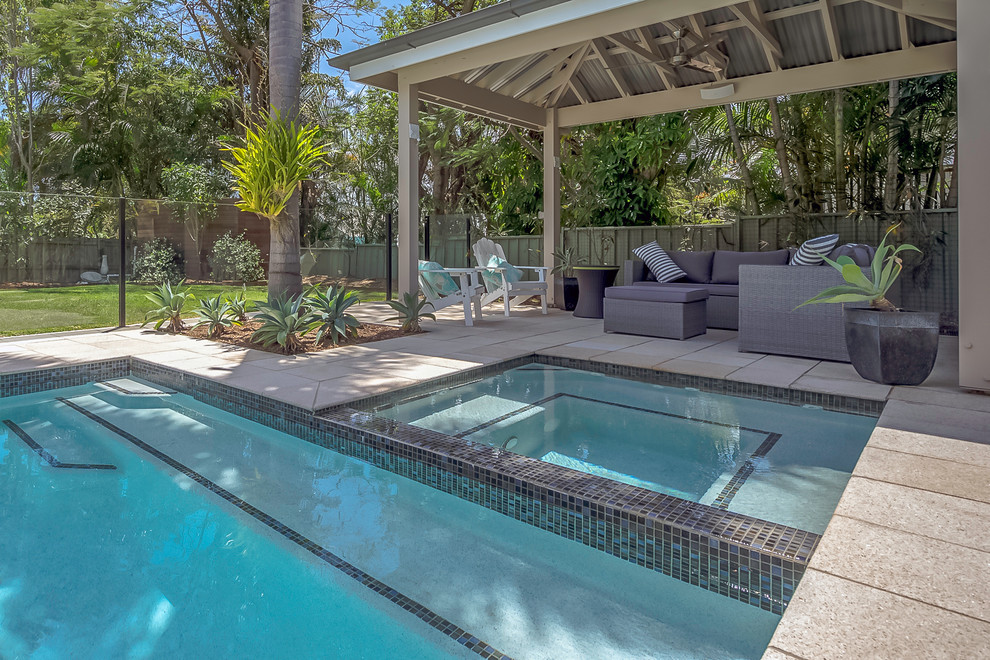 Immagine di una piscina monocorsia tropicale rettangolare di medie dimensioni e dietro casa con una vasca idromassaggio e pavimentazioni in pietra naturale
