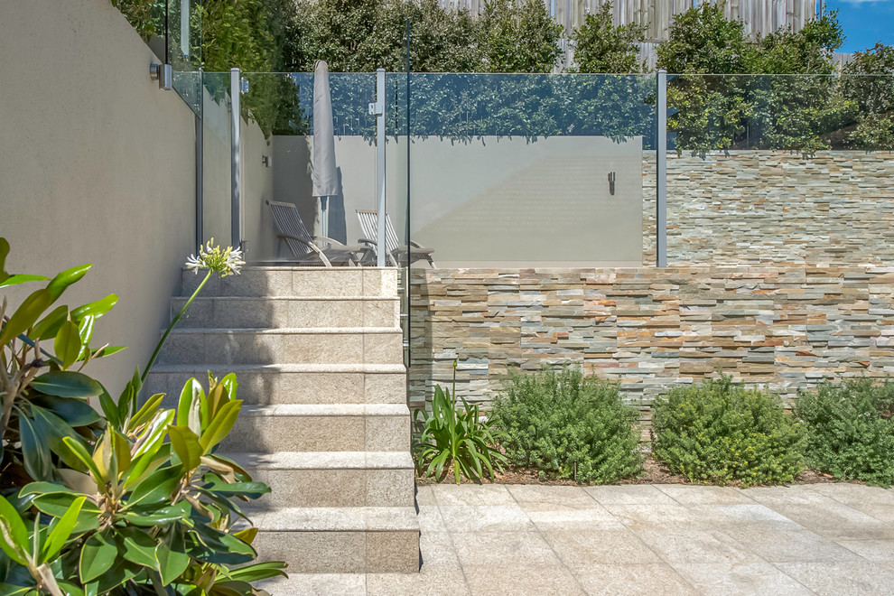 Foto de piscina elevada moderna de tamaño medio a medida en patio trasero con adoquines de piedra natural