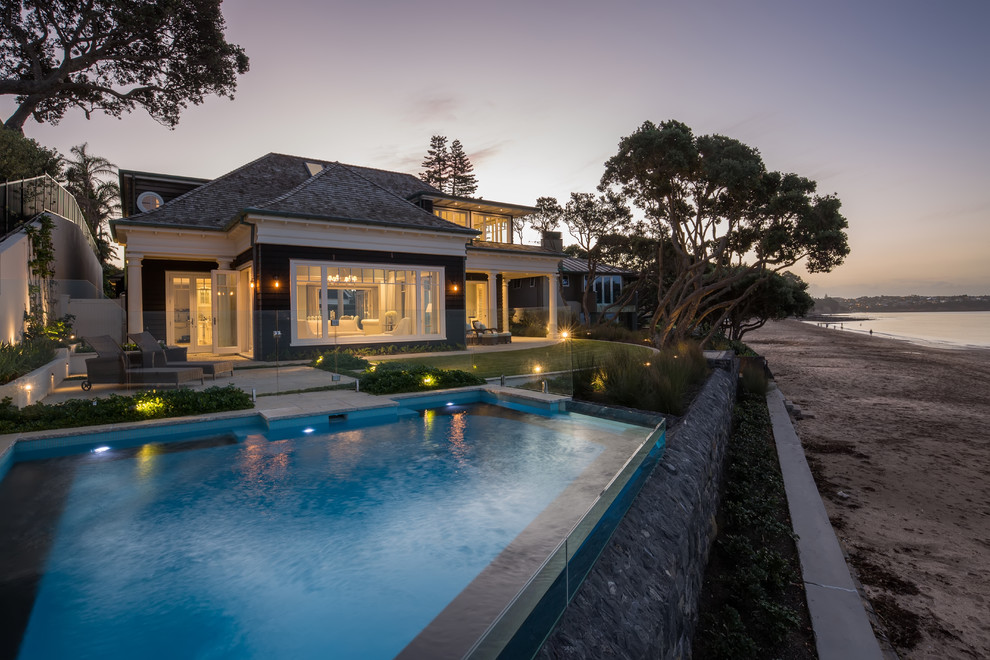 Esempio di una grande piscina a sfioro infinito stile marinaro personalizzata davanti casa con pavimentazioni in pietra naturale