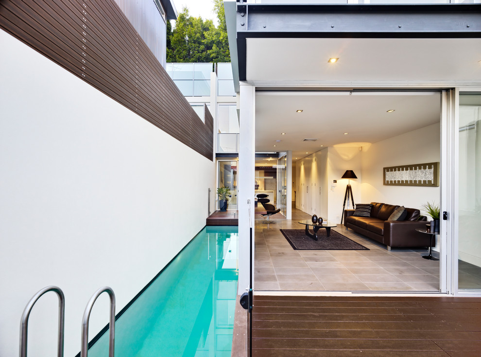 Imagen de piscina alargada contemporánea rectangular en patio lateral con entablado