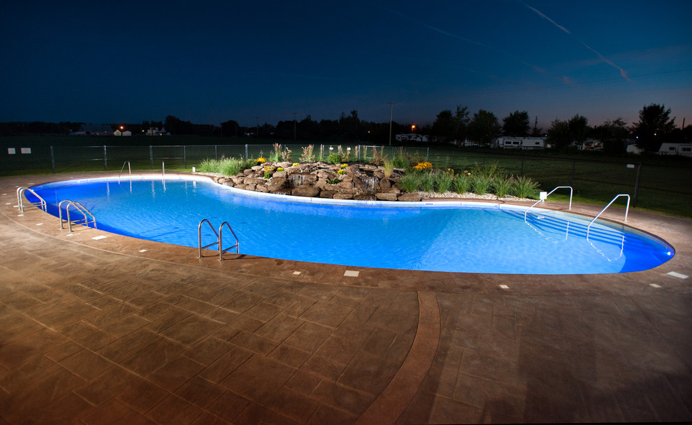 Modelo de piscina con fuente natural rural extra grande en patio con suelo de hormigón estampado