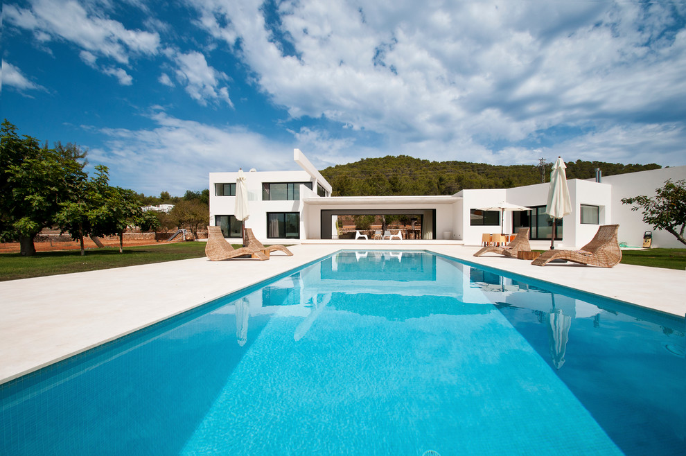 Ejemplo de piscina alargada mediterránea grande rectangular en patio trasero con losas de hormigón