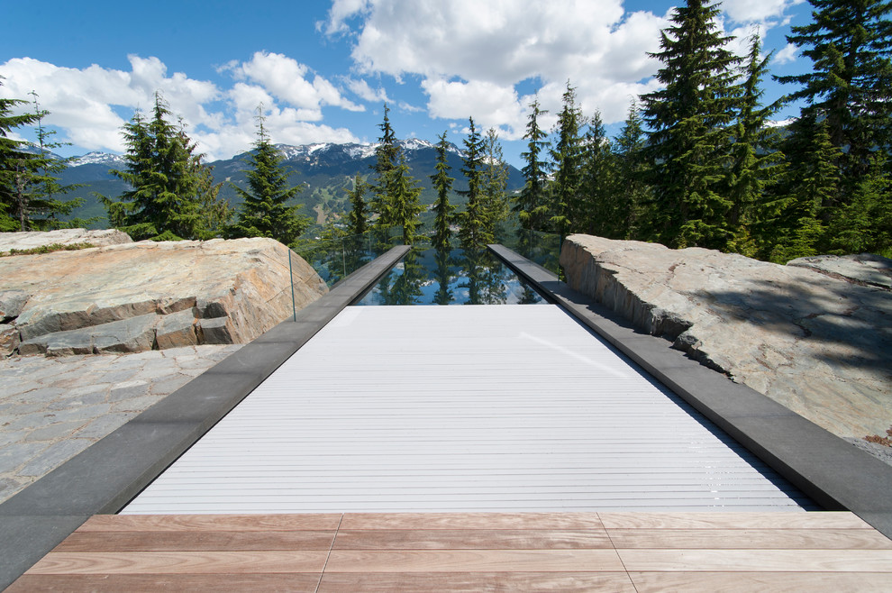 Idée de décoration pour une piscine à débordement design rectangle avec une terrasse en bois.