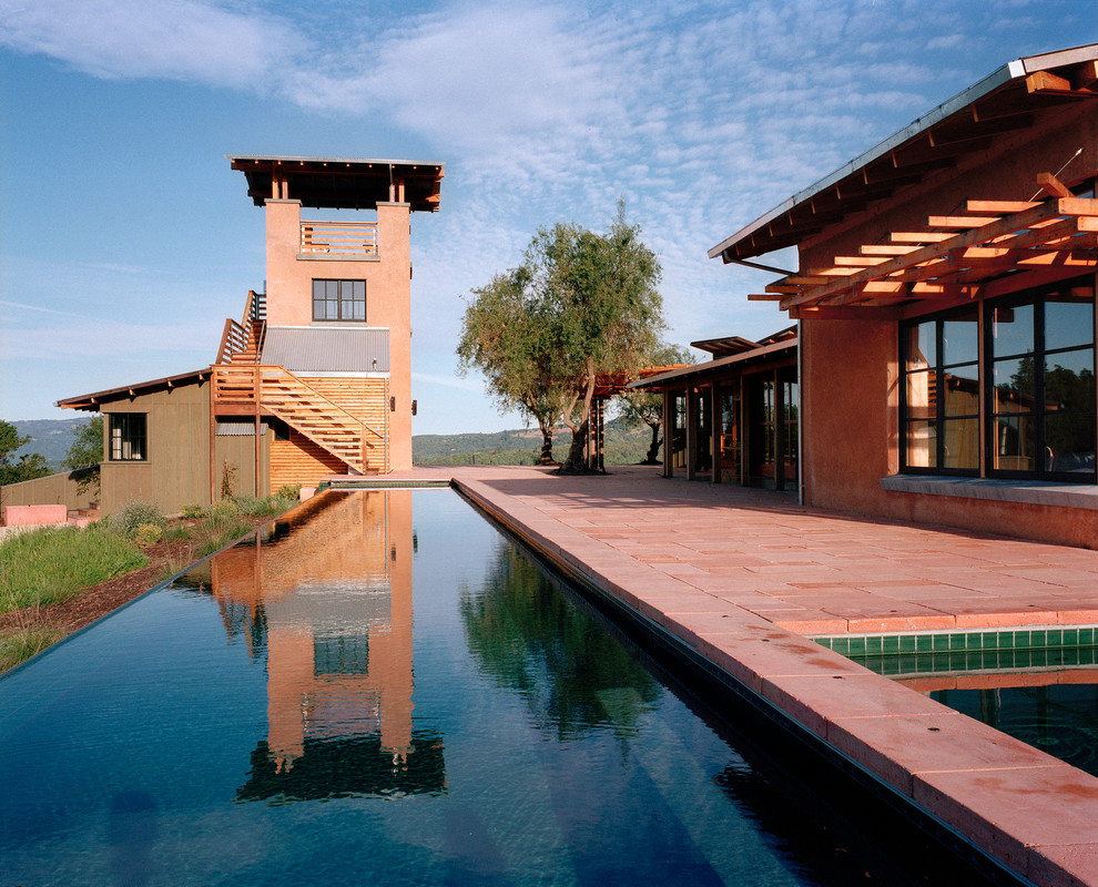 Immagine di una grande piscina a sfioro infinito country rettangolare dietro casa con una vasca idromassaggio