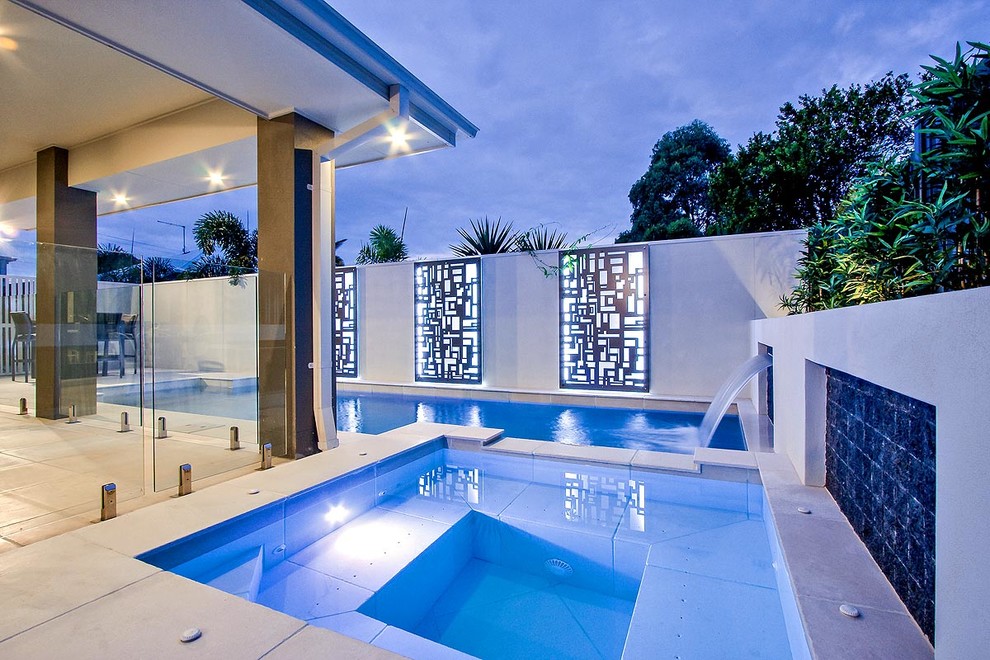 Ejemplo de piscina con fuente alargada moderna pequeña a medida en patio con adoquines de piedra natural