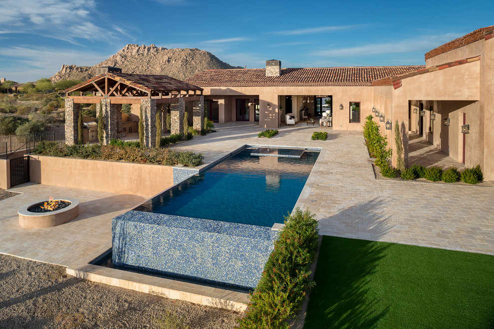 Idée de décoration pour une très grande piscine à débordement et arrière méditerranéenne rectangle avec un bain bouillonnant et des pavés en pierre naturelle.