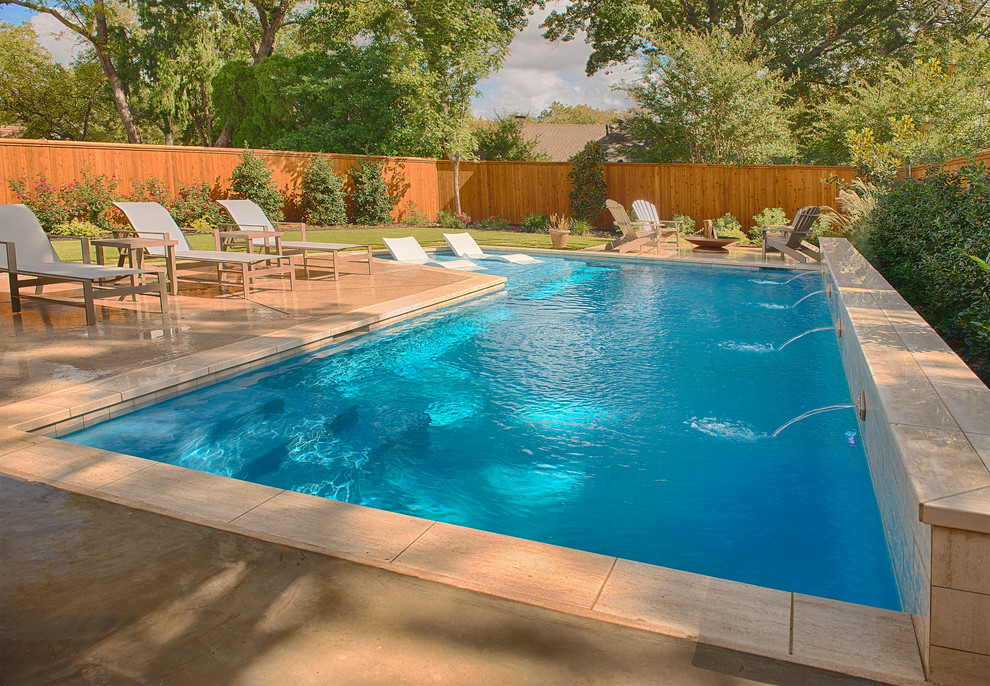 Modelo de piscina con fuente alargada contemporánea de tamaño medio en forma de L en patio trasero con losas de hormigón
