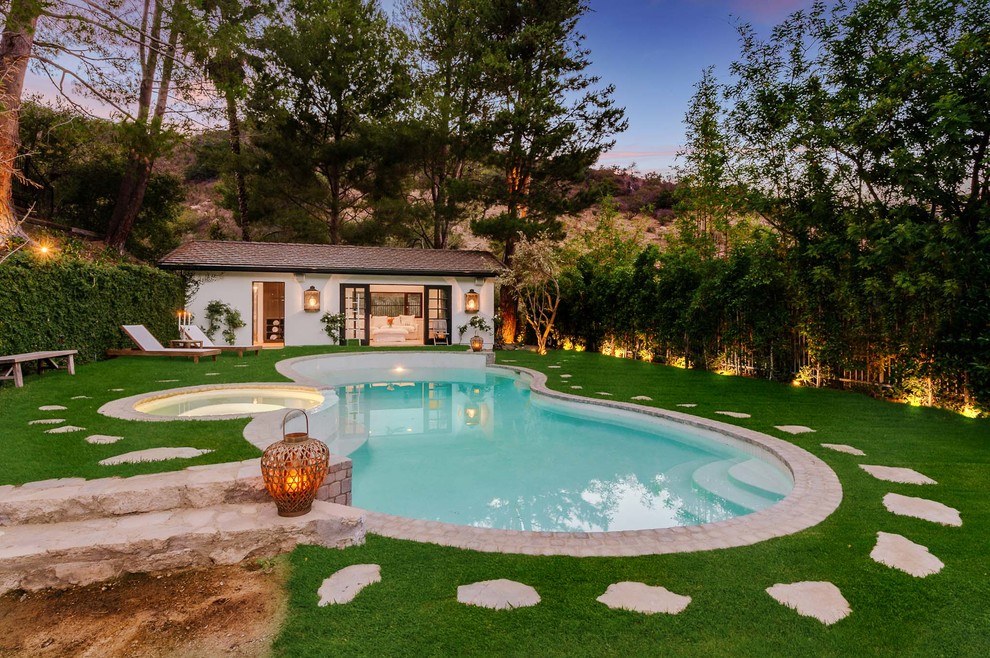 Идея дизайна: большой естественный бассейн в форме фасоли на заднем дворе в средиземноморском стиле с домиком у бассейна