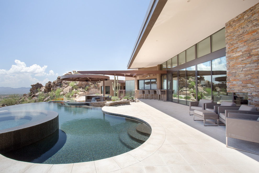 Immagine di una grande piscina a sfioro infinito contemporanea personalizzata con pavimentazioni in pietra naturale