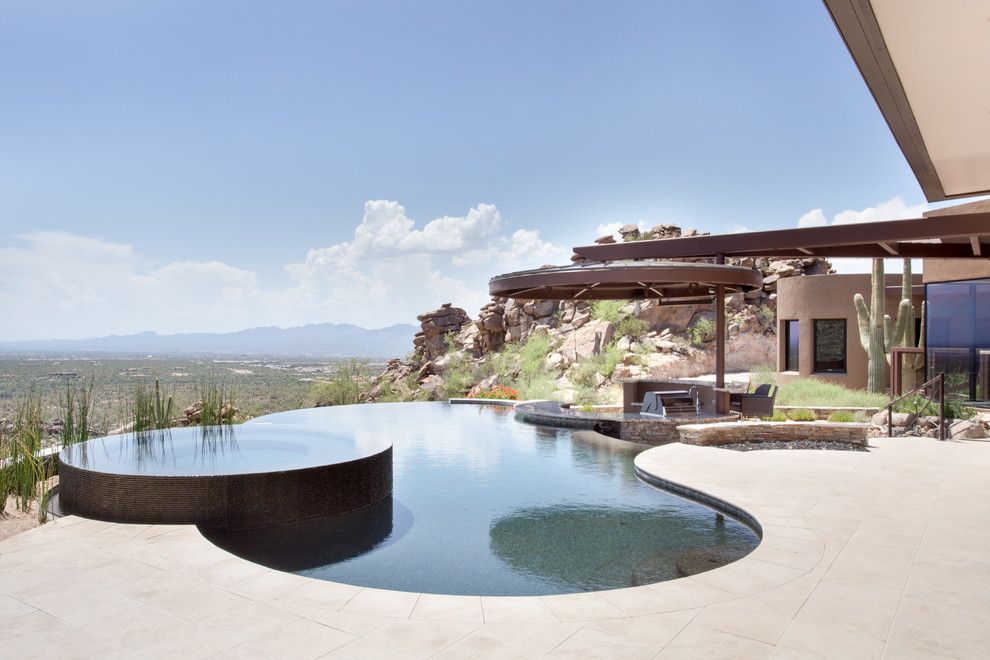 Foto de piscina infinita actual extra grande a medida en patio con losas de hormigón