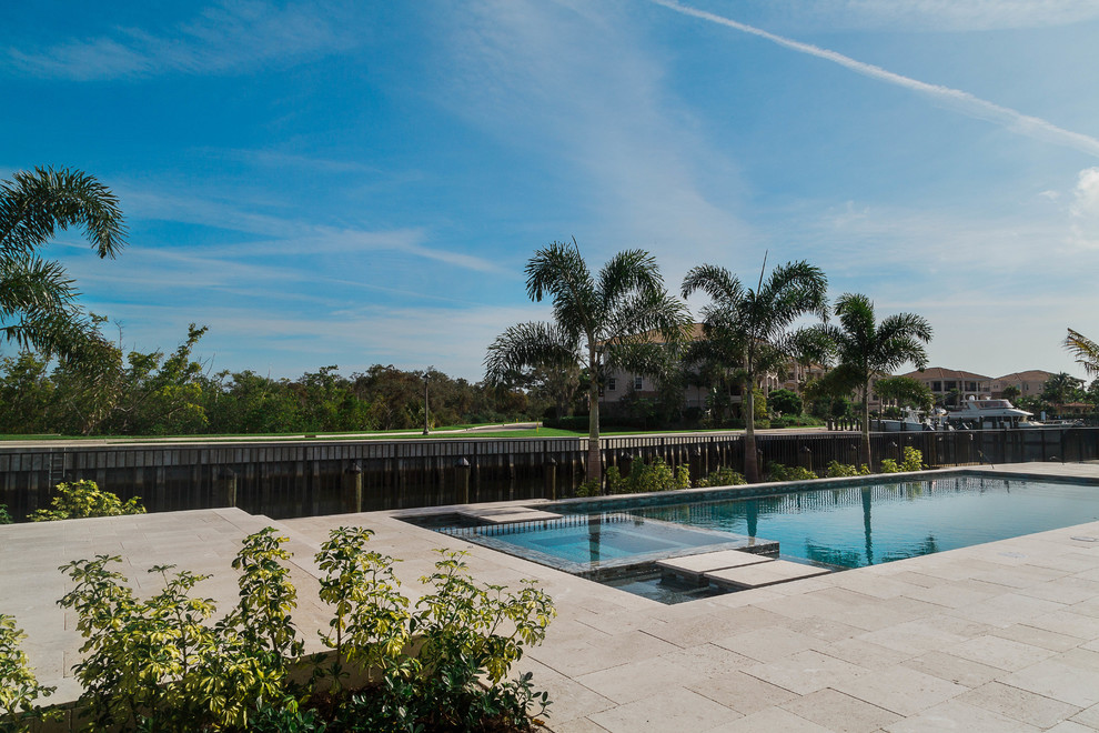 Diseño de piscina tropical de tamaño medio en patio trasero con adoquines de piedra natural