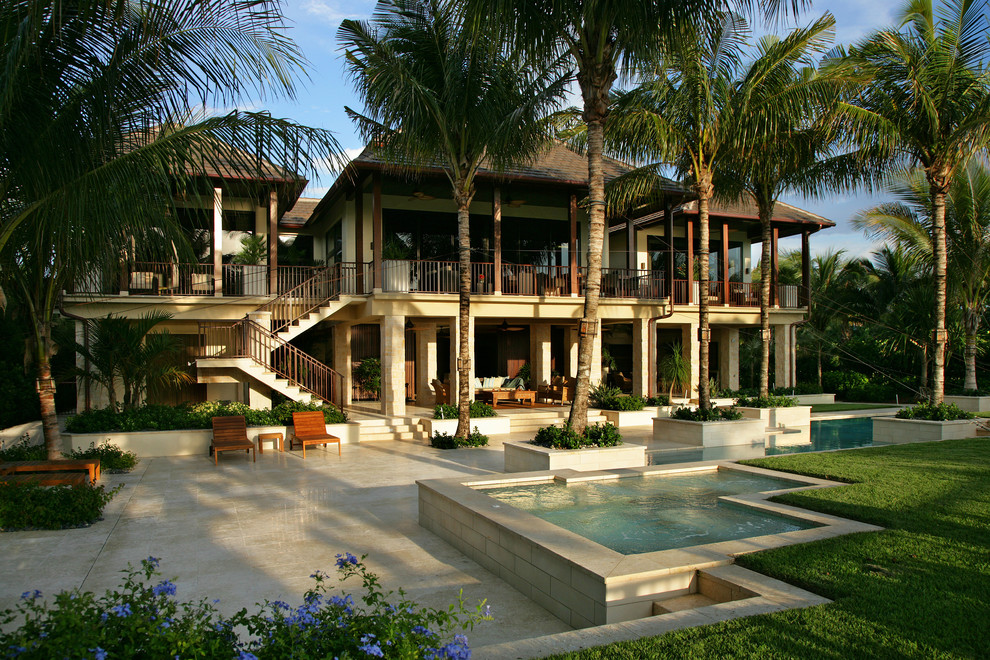 Example of an island style backyard tile and custom-shaped lap pool design in Miami