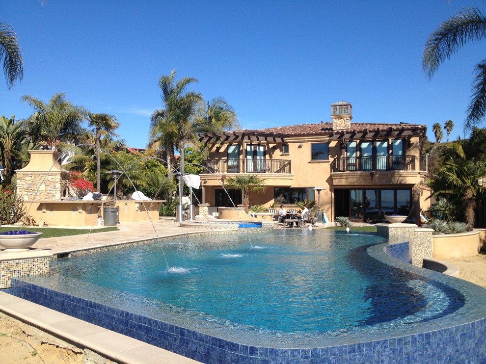 Foto di una grande piscina naturale mediterranea personalizzata dietro casa con fontane e pavimentazioni in pietra naturale