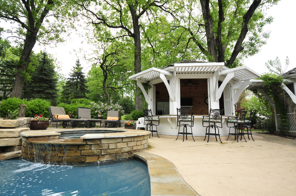 Modelo de piscinas y jacuzzis naturales tradicionales de tamaño medio a medida en patio trasero con losas de hormigón