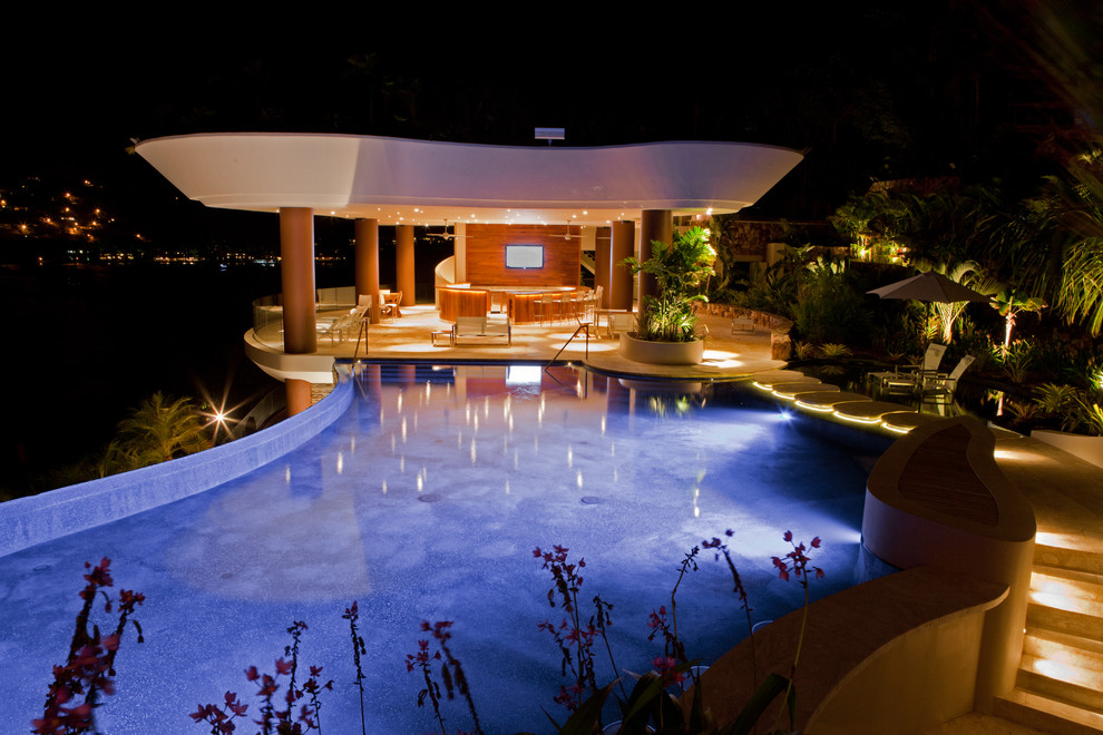Foto de casa de la piscina y piscina infinita exótica extra grande a medida en patio lateral con adoquines de hormigón