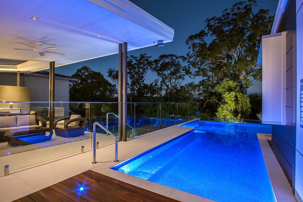 Diseño de piscina con fuente elevada contemporánea grande rectangular en patio con adoquines de piedra natural
