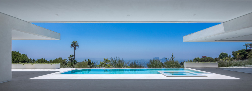 Example of a mid-sized trendy side yard tile and rectangular infinity pool design in Los Angeles
