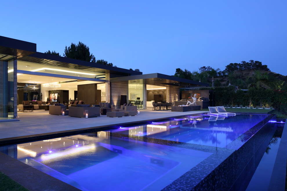 На фото: большой естественный, прямоугольный бассейн на заднем дворе в современном стиле с джакузи и покрытием из бетонных плит